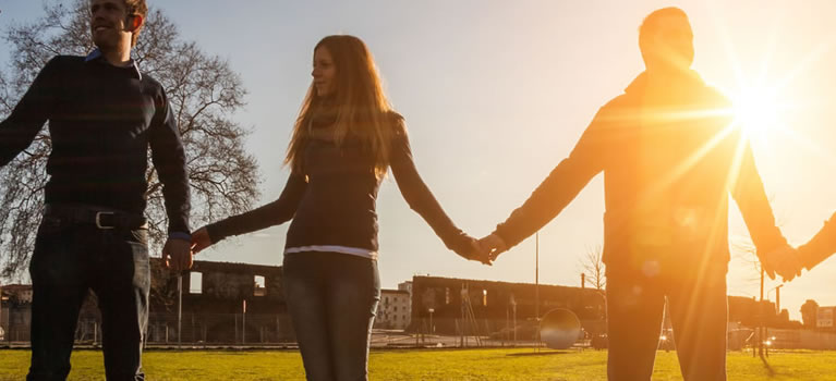 group of people holding hands in the setting sun
