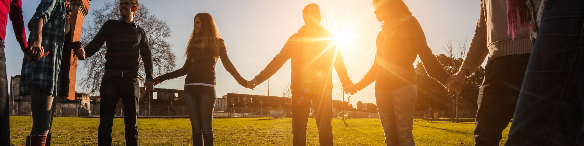 Group of people holding hands in the setting sun